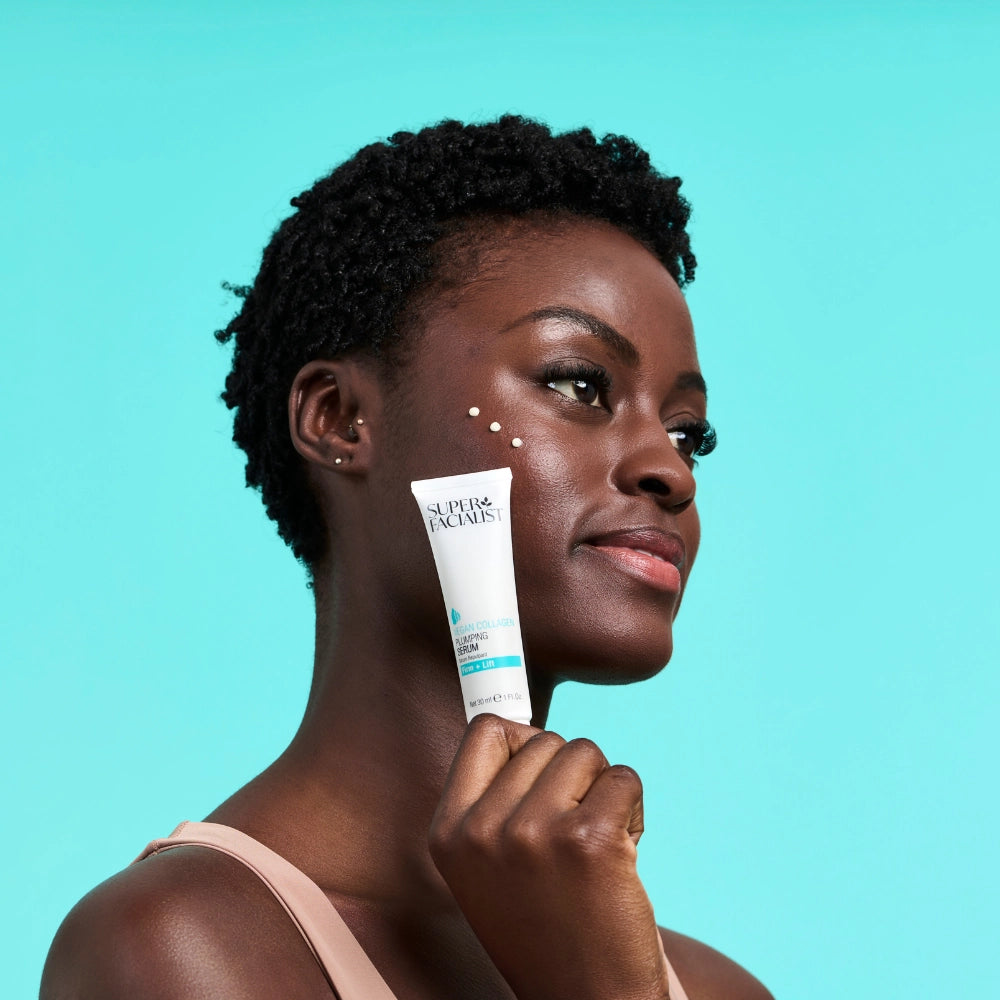 model holding a serum with cream dots on her cheek