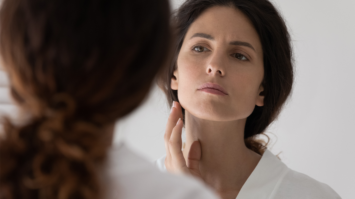 woman assessing her skin the mirror