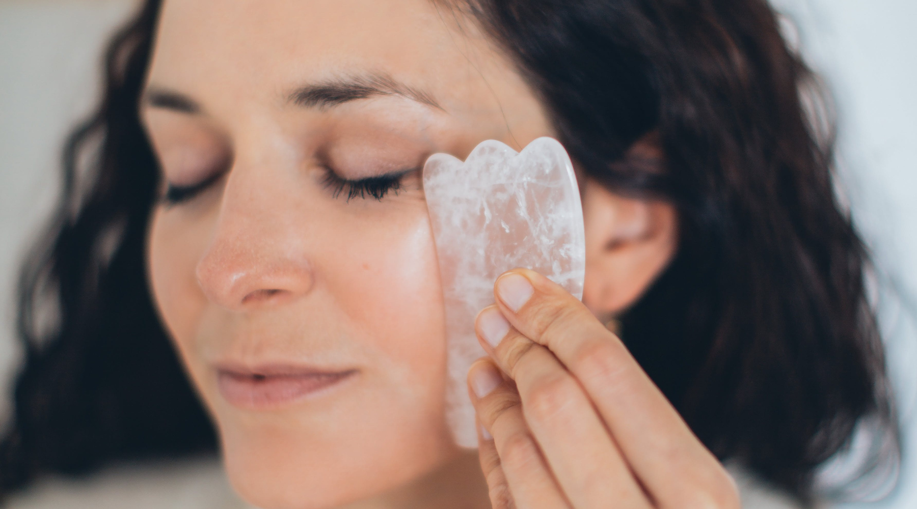 Woman with gua sha doing a facial massage