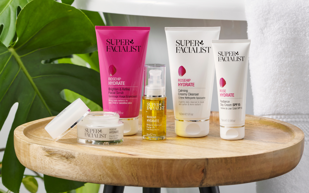 Super Facialist Rosheip Range on table in bathroom next to green plant and white towel 