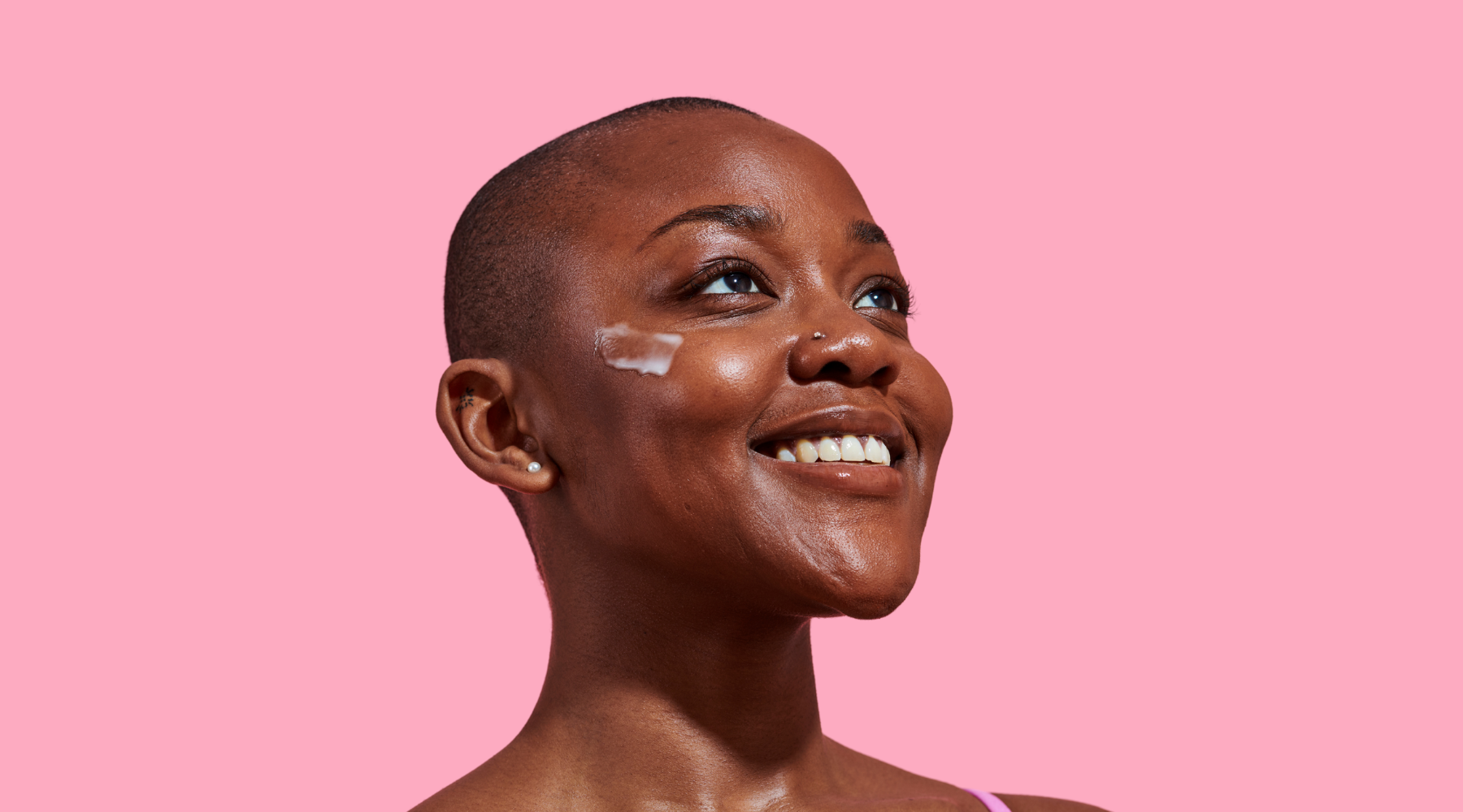 Woman smiling and looking away with a cream swatch on her cheekbone