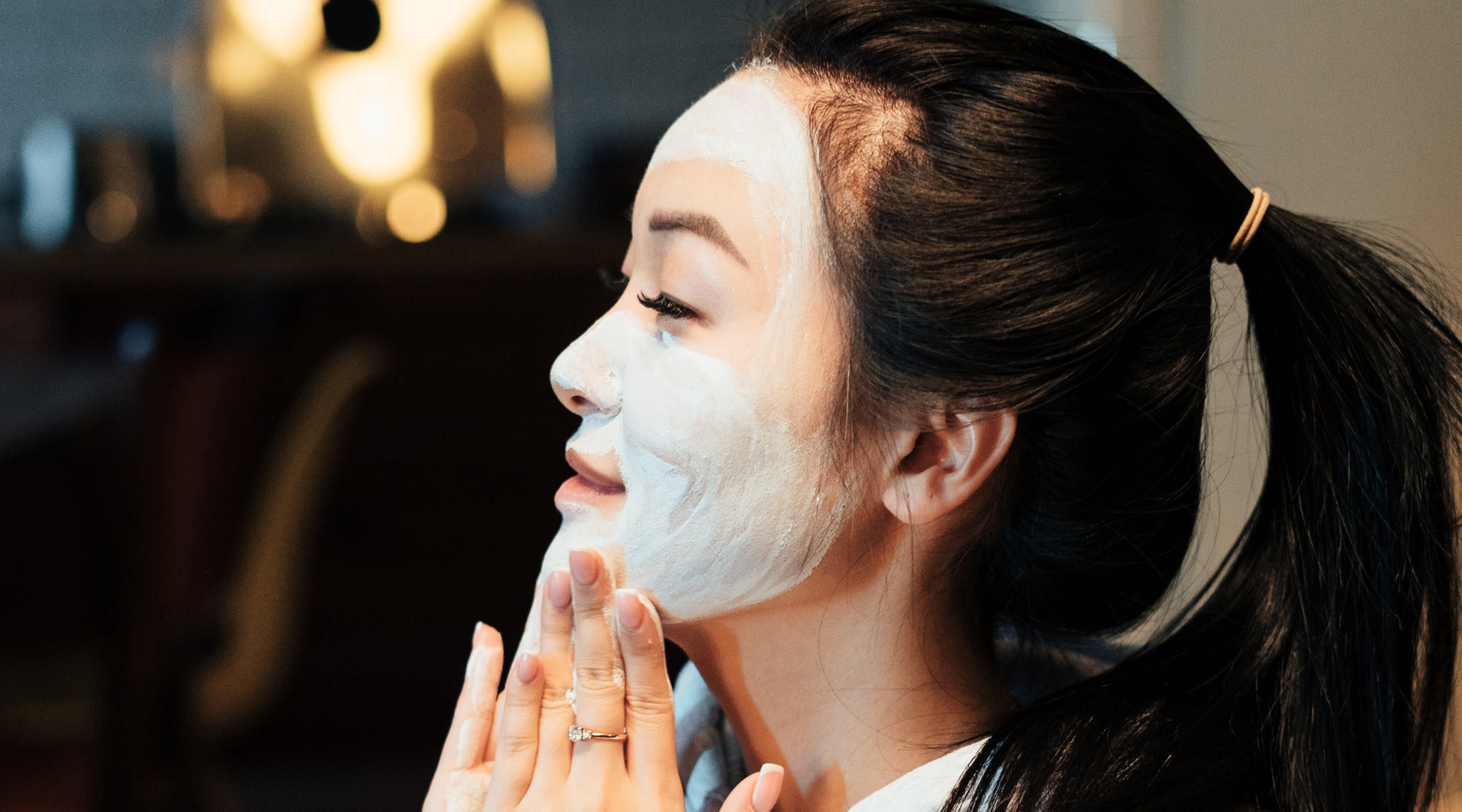 woman applying clay mask to face