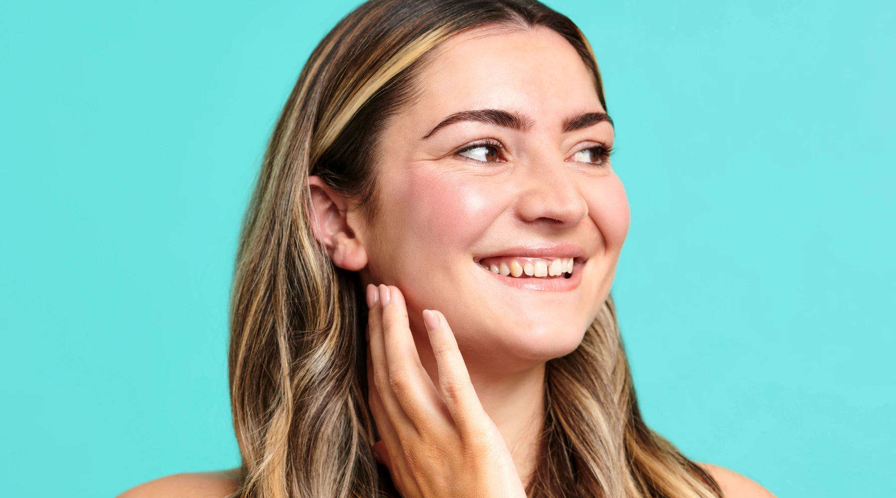 Woman wearing skincare smiling while looking away