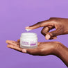 finger dipping into an open jar of retinol night cream