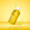 Vitamin C Cleansing Oil bottle tilted against a yellow background with oil dripping ontop of it