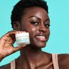 model holding day cream frosted jar next to face