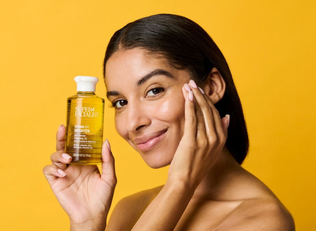 woman holding vitamin c cleansing oil with one hand 