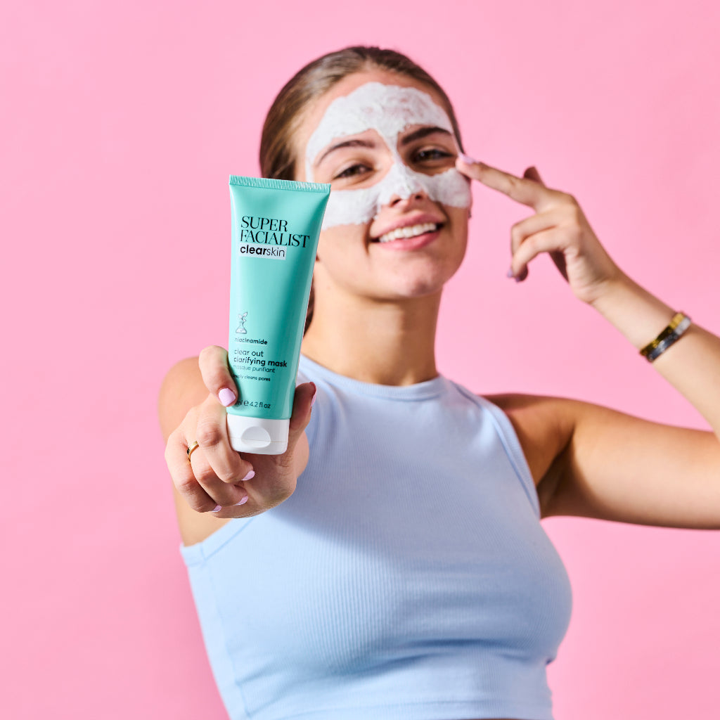 Model applying the product onto her face while holding the Clarifying Mask tube in another hand