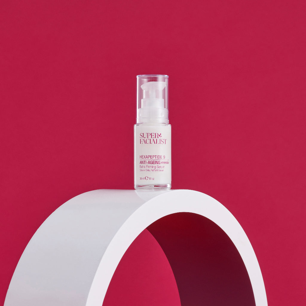 Hexapeptide 9 serum bottle on top of circular white prop in front of red background
