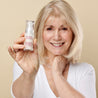Model holding hexapeptide 9 serum towards the camera while smiling