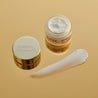 Hexapeptide 9 eye cream glass jar opened on gold table with cream swatch next to the jar