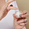 Hand dipping a finger inside the hexapeptide 9 eye cream jar