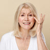 Model dabbing the hexapeptide 9 eye cream under her eyes while smiling and looking at the camera