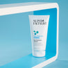 Cleanser tube pack shot inside a white square prop against a blue background