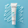 Firming Serum tube on top of squiggly serum texture pattern on light blue table