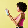 Teen model standing sideways holding the Clear Skin Exfoliator tube with both of her hands while looking at the tube