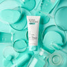 Daily Moisturiser tube on turquoise background with turquoise liquid  pouring out of glass containers around it