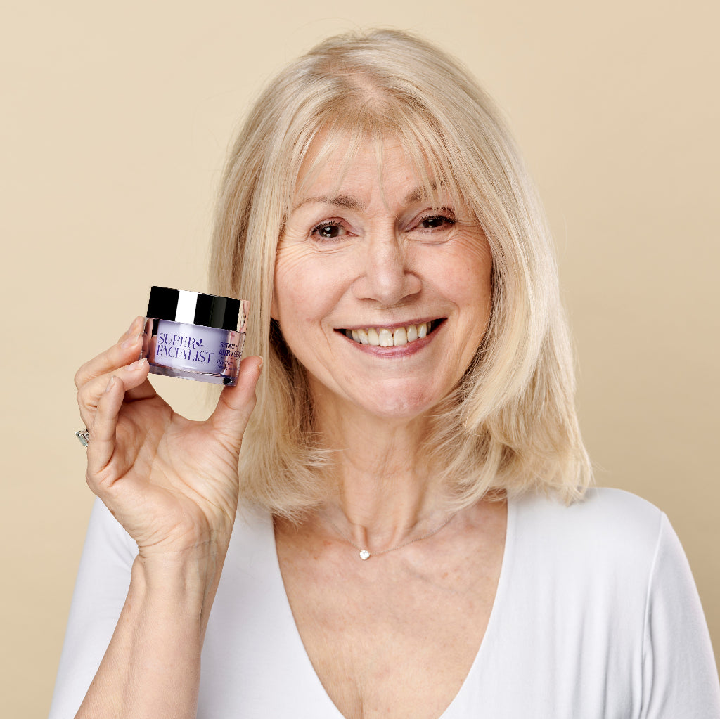 Model holding the retinol day cream jar next to her face while smiling