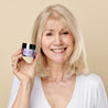 Model holding the retinol day cream jar next to her face while smiling