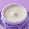 Smooth day cream inside a glass jar on purple background