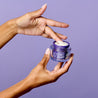 Scooping out night cream from a jar with a finger