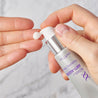 Hands hoding the retinol serum tube and pumping out a small pea size of the serum on fingers