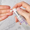 Hands hoding the retinol serum tube and pumping out a small pea size of the serum on fingers