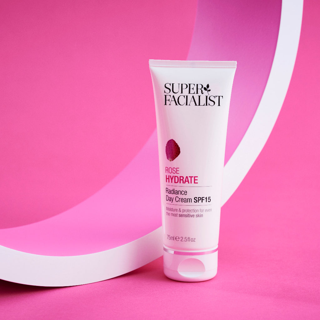 Rose day cream packshot infrot of a white circular prop against a bright pink background