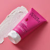 Rosehip tube next to facial scrub swatch on pink background