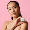 Model holding the night cream jar against her shoulder while looking into the camera