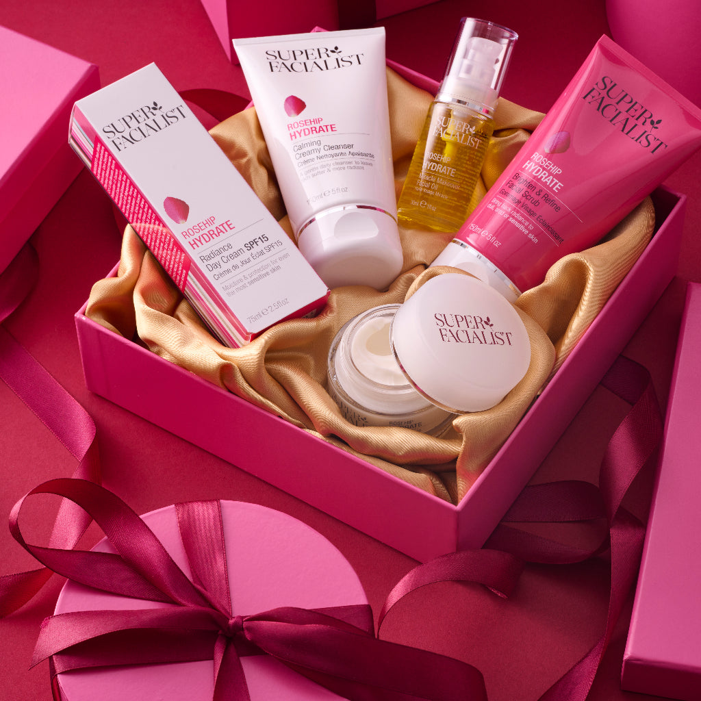 Full rosehip range laid out inside a pink gift box surrouned by pink ribbon and more pink gift boxes