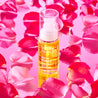 Rosehip Oil bottle ontop of a pink mirror surrounded by pink rose petals