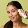Model pumping out gel moisturiser onto her check while looking at the camera
