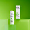 Salicylic acid moisturiser tube next to carton box on green large cubes against green background