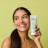 Model holding salicylic acid clay mask next to her face while looking away