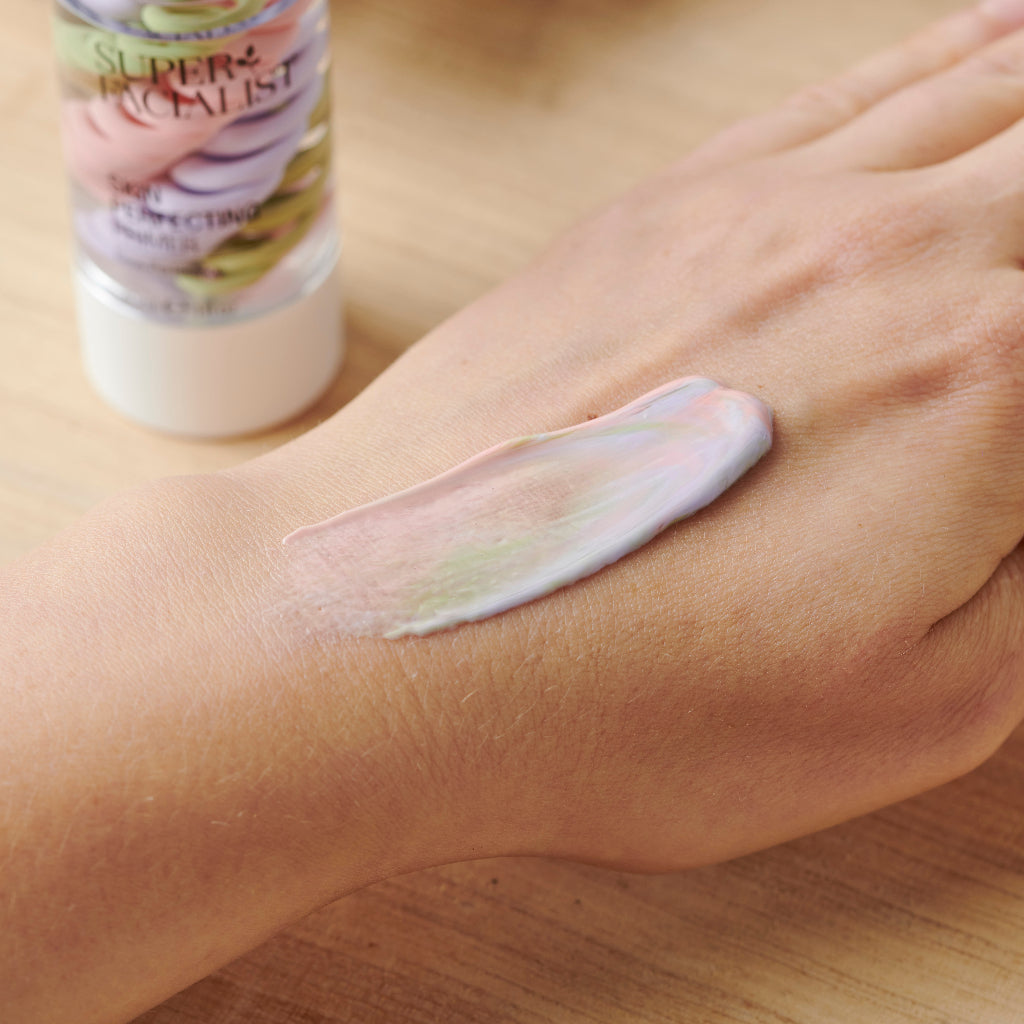 Creamy pink, green and purple primer swatch on the back of a hand