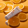 Vitamin C moisturiser bottle on top of orange slices on orange mirror table