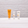 Micro polish tube next to eye cream tube next to daily moisturiser on white wooden table and white brick wall