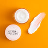 Birds eye view of  night cream jar with super facialist logo on the lid and cream product texture swatch next to it