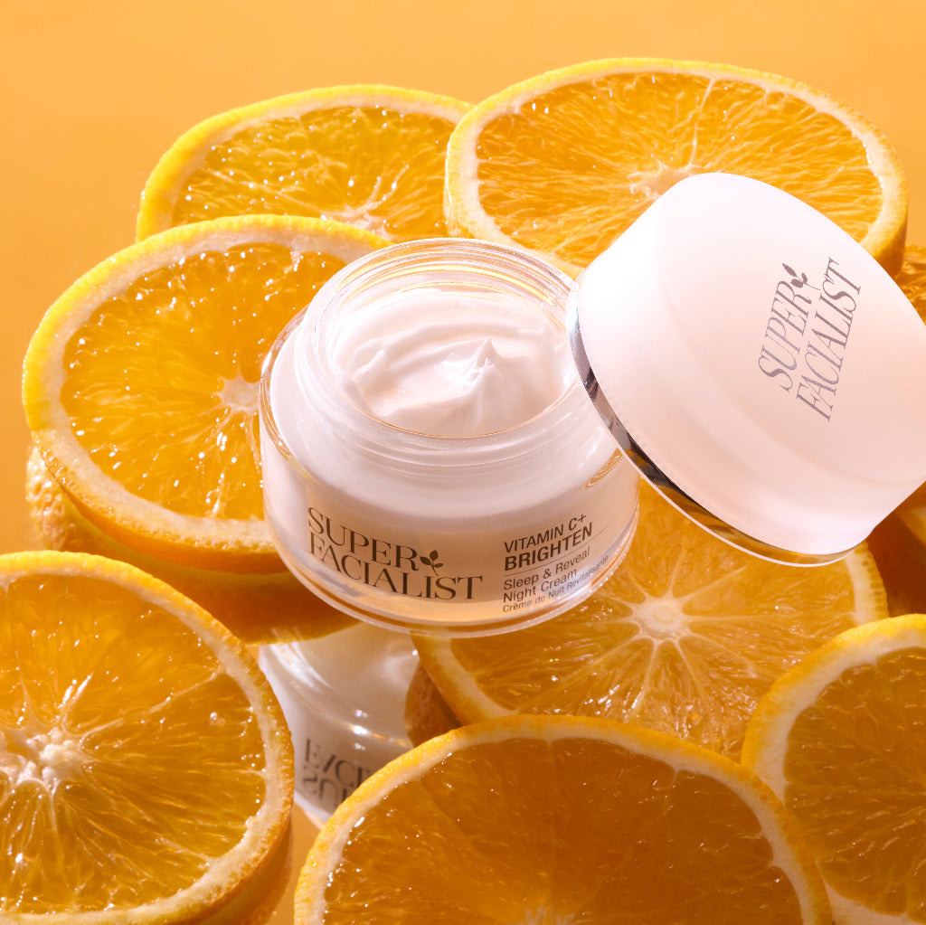 Night cream glass jar on top of orange slices with lid open
