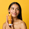 Model headshot holding vitamin c daily micro polish wash bottle while looking away