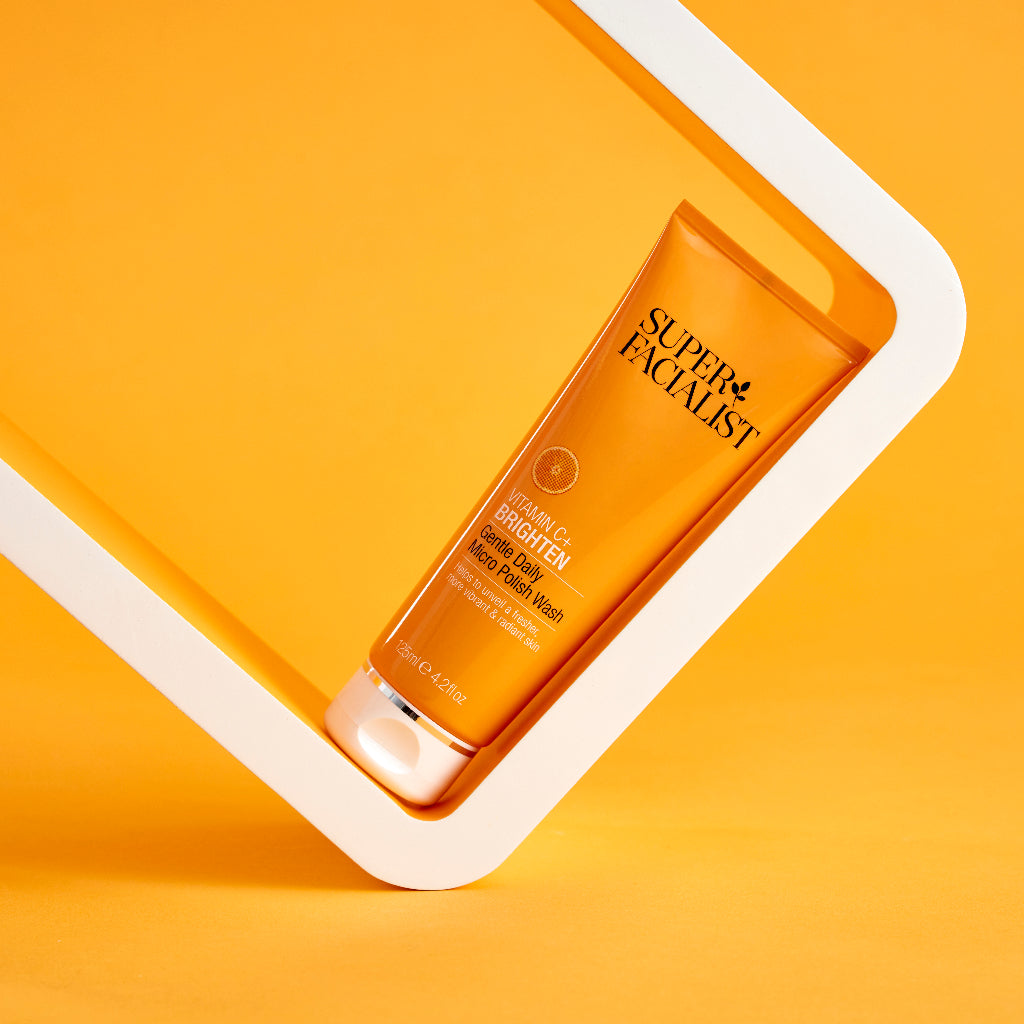 Vitamin C daily polish bottle inside a tilted white box against orange background