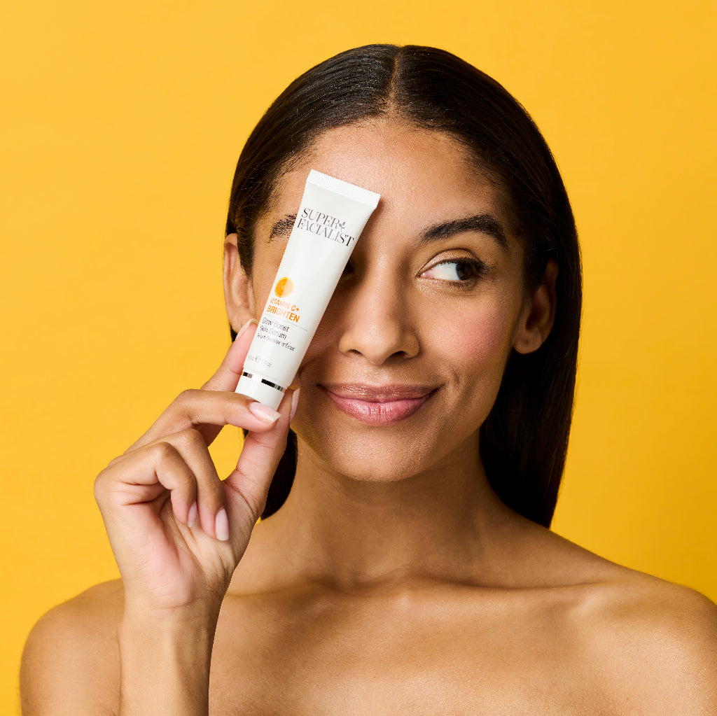 Model headshot holding Vitamin C Serum over her eye while looking away