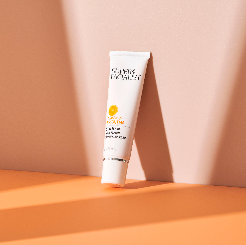 Vitamin C serum tube leaning against a wall with shadows around it